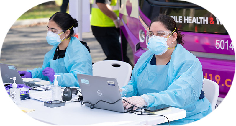 bus-exterior-nurses-at-table-laptops-crop